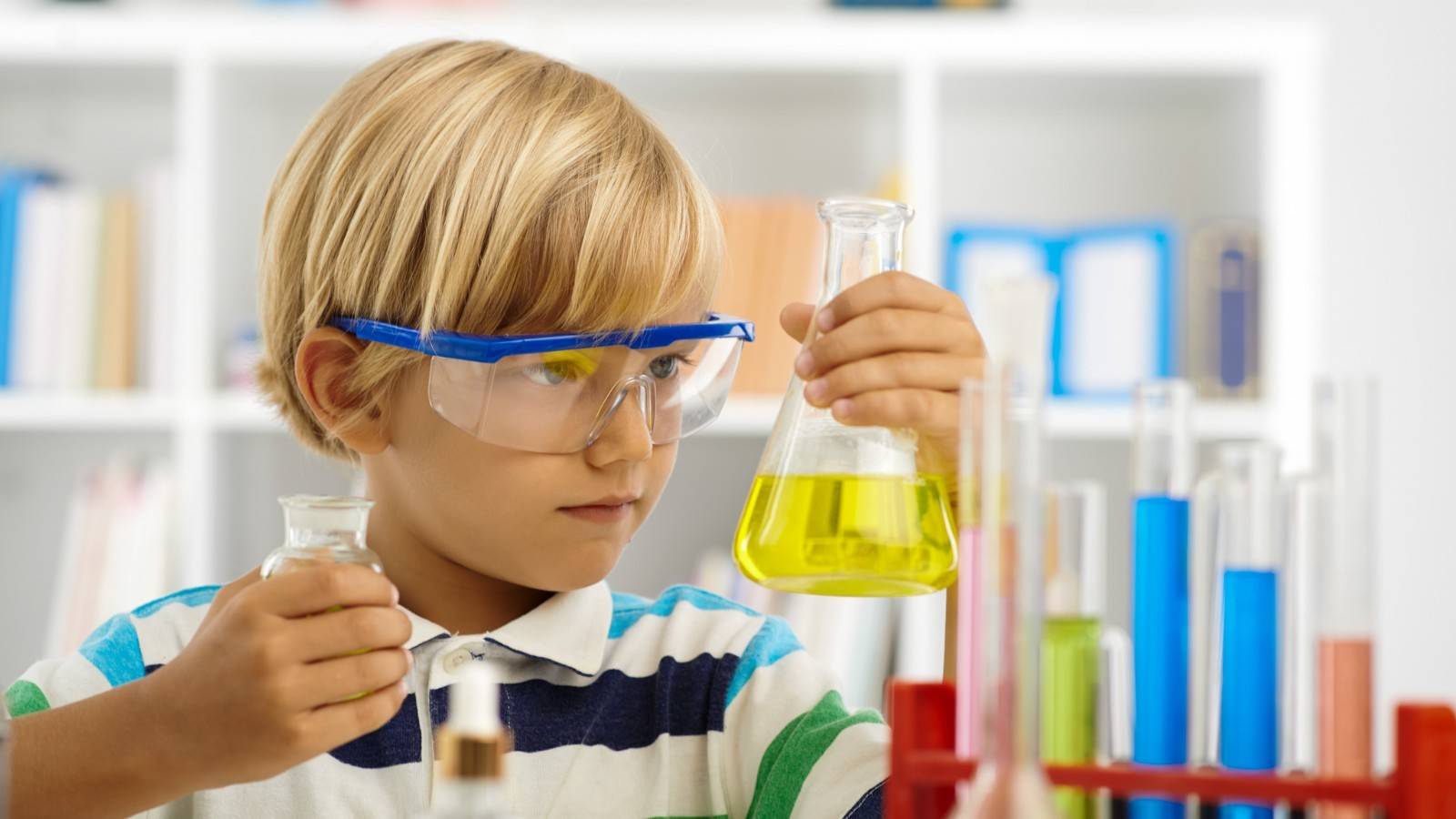 Boy in field looking at grass and flowers through a magnifying glass