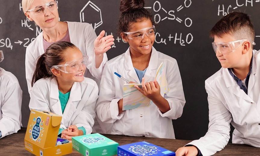 2 boys wearing mad science lab coats working on their mad science loop lab box competing one of the experiments